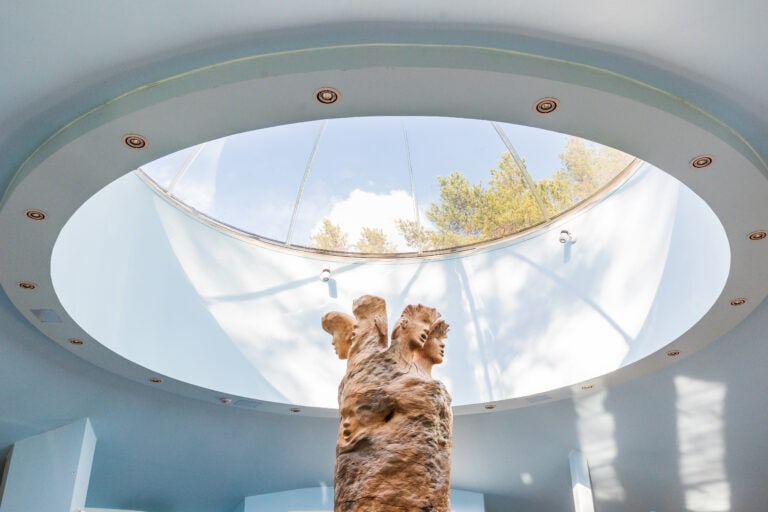 Taiteilija Eeva Ryynäsen puuveistos ateljeessa kattoikkunan alla.